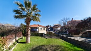A residential area with a palm tree, a stone wall, and houses with red-tiled roofs. - Apartment "Villa Votistis A1" with Mountain View, Garden & Wi-Fi (Lefkadas)
