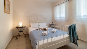 A neatly made bed with a white headboard, a bedside table with a lamp, and a window with sheer curtains. - Apartment "Villa Votistis A1" with Mountain View, Garden & Wi-Fi (Lefkadas)