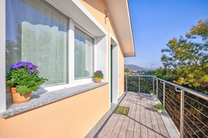 En balkon med plantekasser, et vindue med gardiner og en klar himmel.