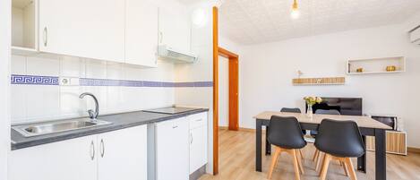 A modern kitchen with white cabinets, a black countertop, and a built-in microwave.