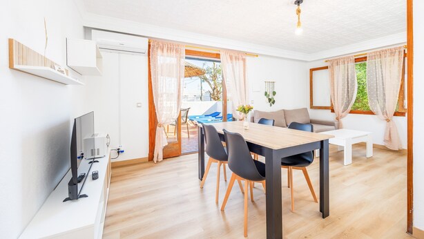 Un salon moderne comprenant un coin repas, un téléviseur et une vue sur l’extérieur.