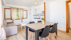 Un salon moderne comprenant un canapé, une table à manger et des chaises, un coin cuisine et un plafond doté d’un luminaire.