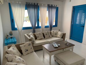 Een woonkamer met een beige bank, een houten salontafel en een blauwe deur.