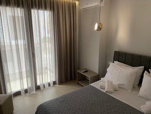 Habitación de hotel con cama, almohadas, mesita de noche, control remoto y lámpara colgante.