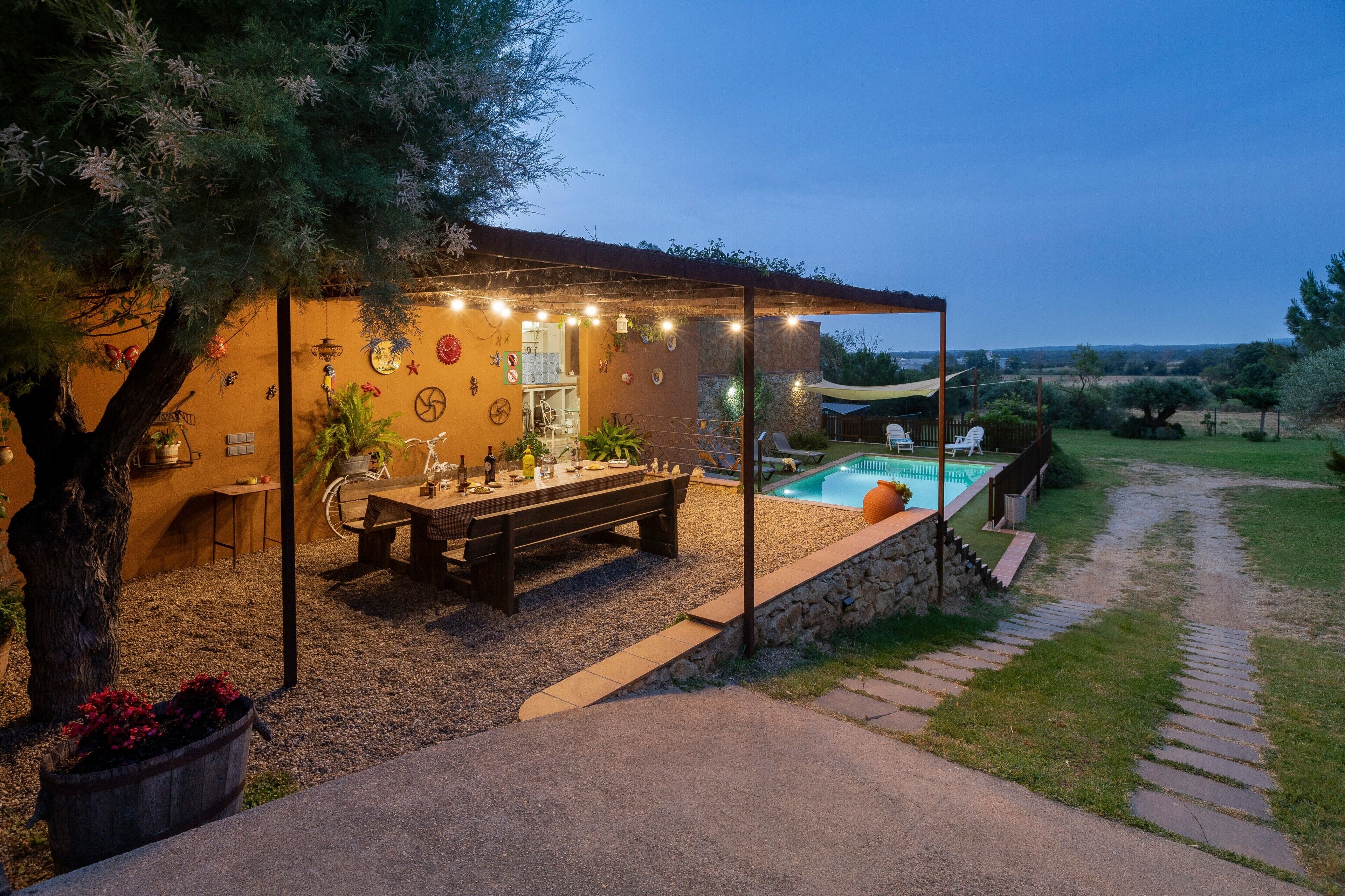 Un área de comedor al aire libre con piscina, muros de piedra y una pérgola.