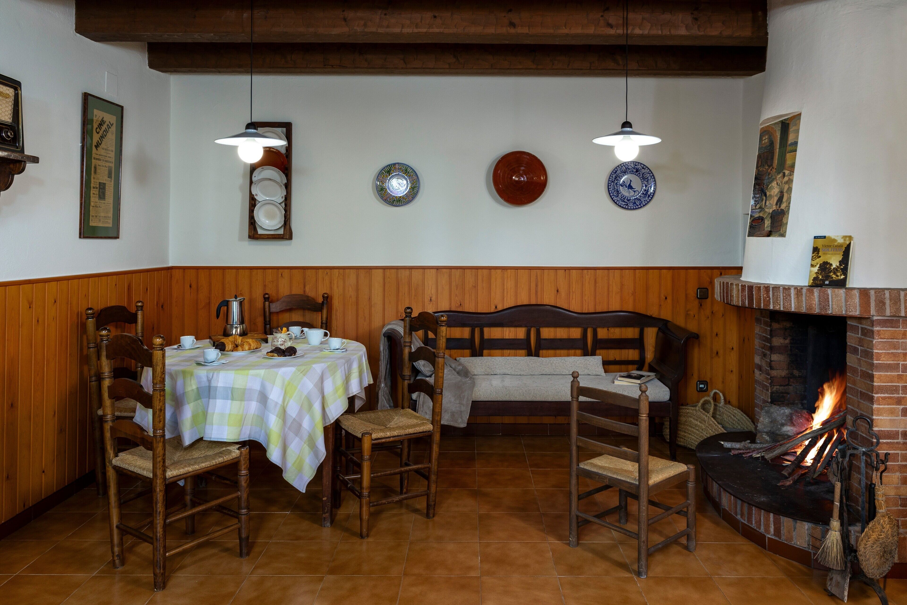 Un coin repas avec des meubles en bois, une cheminée et des assiettes décoratives accrochées au mur.