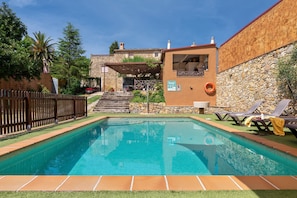 A swimming pool with a stone wall and a wooden fence.