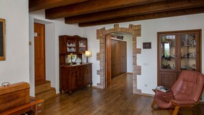 Une pièce avec un plancher en bois, un fauteuil à bascule, une armoire en bois et une arche en briques.