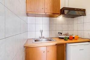 A kitchen with a sink, wooden cabinets, a stove, and a dishwasher.