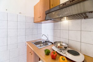 A kitchen with a sink, stove, and wooden cabinets. - Nikiana Club Studio 10 with Mountain View & Wi-Fi (Lefkada)