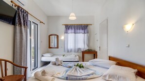A hotel room with a bed, a chair, a window with curtains, a mirror, and a wall-mounted light fixture. - Nikiana Club Studio 6 with Mountain View & Wi-Fi (Lefkada)