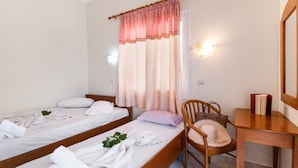 A room with two single beds, a wooden chair, a desk, and a window with curtains. - Nikiana Club - Studio 5 Apartment-Studio with Sea View & Wi-Fi (Lefkada)