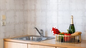 A kitchen with a stainless steel sink, a tiled backsplash, and a fruit basket with a bottle. - Nikiana Club - Studio 5 Apartment-Studio with Sea View & Wi-Fi (Lefkada)