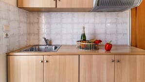 A kitchen with a stainless steel sink, wooden cabinets, a built-in range hood, and a fruit basket with a red bell pepper. - Nikiana Club - Studio 5 Apartment-Studio with Sea View & Wi-Fi (Lefkada)