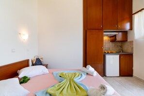 A hotel room with a bed, a small kitchenette, and a bathroom.