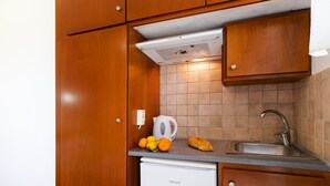 Una cuina compacta amb armaris de fusta, forn integrat, rentapesos i nevera petita.