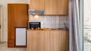 A compact kitchen with wooden cabinets, a built-in microwave, a small refrigerator, and a sink. - Apartment-Studio "Nikiana Club - Studio 2" with Sea View & Wi-Fi (Lefkada)