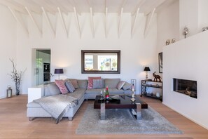 A modern living room with a sectional sofa, a glass coffee table, and a fireplace.