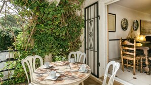 A round table with chairs, a white door, and a wall with a black gate. - Holiday Home 'Villa Montgó Parc Con Piscina' with Mountain View, Shared Pool and Air Conditioning (L'Escala)