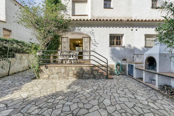 A courtyard with stone flooring, a staircase, outdoor furniture, and a brick oven.