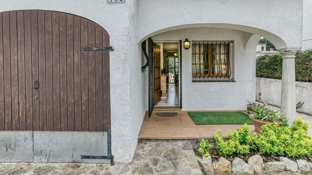 A house with a large wooden door, a stone pathway, and a small garden with plants. - Holiday Home 'Villa Montgó Parc Con Piscina' with Mountain View, Shared Pool and Air Conditioning (L'Escala)