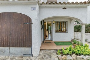 A house with a large wooden door, a stone pathway, and a small garden with plants.