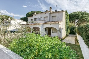Eine weiße Villa mit Ziegeldach, bogenförmigen Durchgängen und einem gepflasterten Weg zum Eingang.