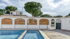 A swimming pool with a tiled deck, white walls with decorative wooden lattice windows, and a gate. - Holiday Home 'Villa Montgó Parc Con Piscina' with Mountain View, Shared Pool and Air Conditioning (L'Escala)