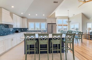A modern kitchen with a central island, bar stools, and a dining area with chairs.
