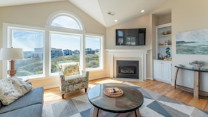 A living room with a fireplace, a sofa, a chair, a coffee table, and a TV mounted on the wall. - Make Lasting Memories at 'Memory Maker' | Pool, Hot Tub, Game Room | Perfect for Large Families (Corolla)