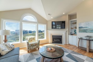 A living room with a fireplace, a sofa, a chair, a coffee table, and a TV mounted on the wall.