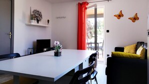Un soggiorno moderno con zona pranzo, divano e televisore.