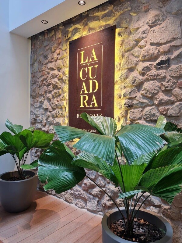 A stone wall with a sign reading "LA CUDRA" and potted plants in the foreground.