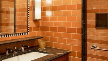 A bathroom with a sink, mirror, and tiled walls.