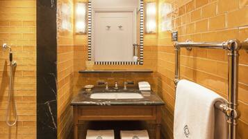 A bathroom with a marble sink, a mirror, a towel rack, and a shower.