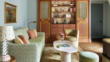 A living room with a patterned sofa, a coffee table, a bookshelf, and a decorative ceiling light.