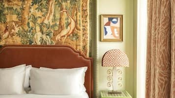 Um quarto com uma cama grande, um tapeçário, uma mesa de cabeceira verde e um quadro na parede.