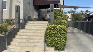 Un edificio con fachada de concreto, una escalera de concreto y una reja metálica.