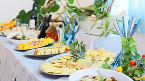 A buffet table with various dishes, including fruits and vegetables, and decorative plants. - Hotel Ali d'Oro (Rimini)
