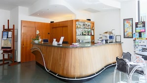 A reception area with a wooden counter, a map display, and a bar area with various bottles. - Hotel Ali d'Oro (Rimini)