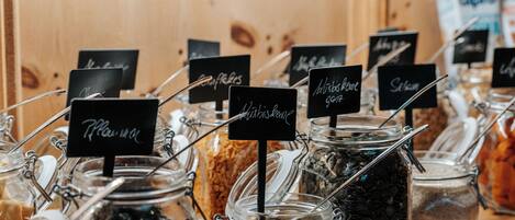 A display of various food items in glass jars with labels, arranged on a wooden surface.