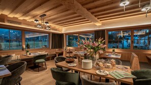 Un rincón comedor acogedor con mesas y sillas de madera, un florero con flores y vistas al exterior.