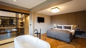 Un dormitorio moderno con una cama grande, una bañera y un televisor en la pared.