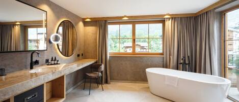 A modern bathroom with a large mirror, a bathtub, and a window with curtains.