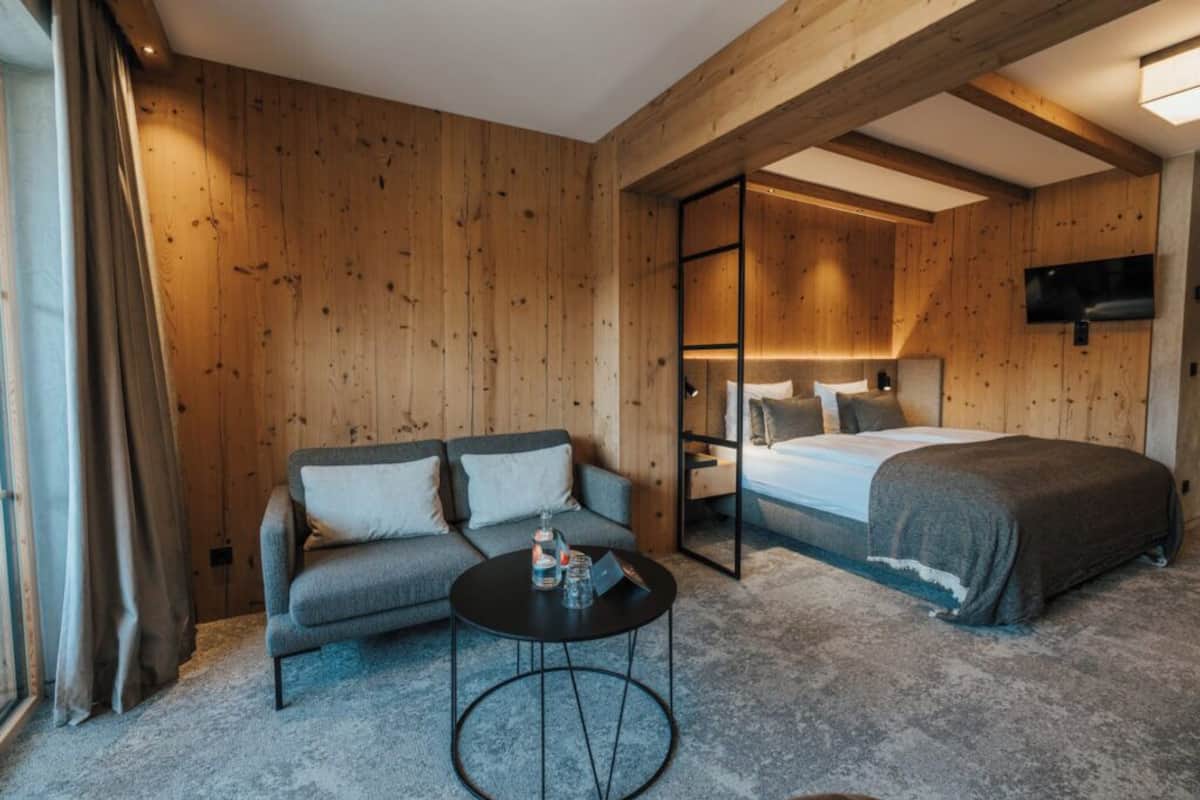 A wooden-paneled room with a sofa, a bed, and a small round table.