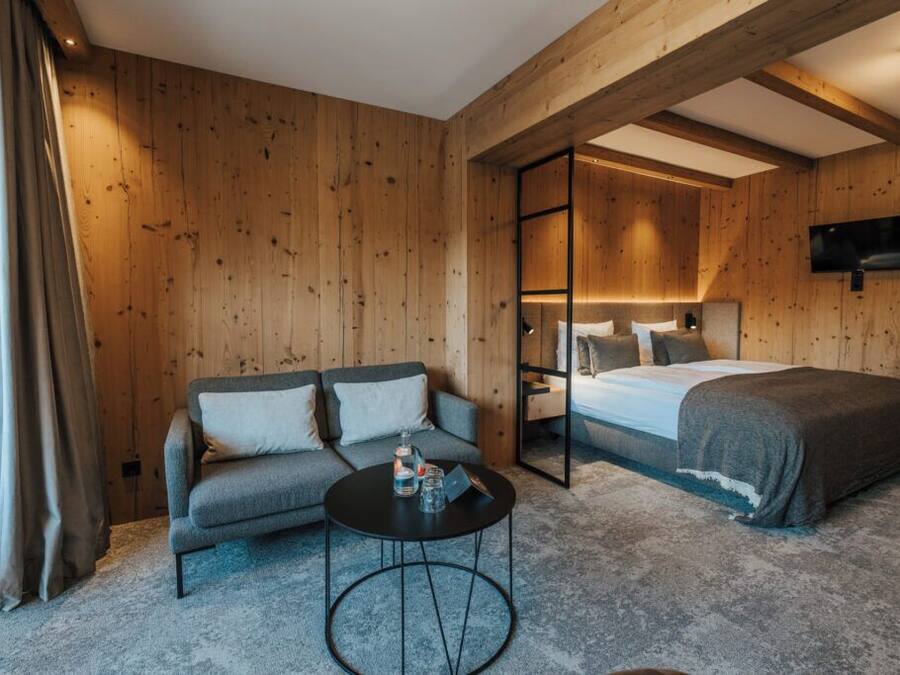 A wooden-paneled room with a sofa, a bed, and a small round table.
