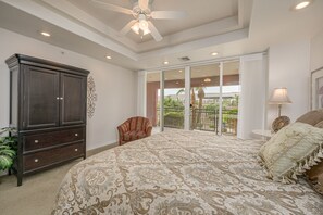 Une chambre spacieuse avec un grand lit, une commode en bois foncé, un fauteuil et un balcon avec vue.