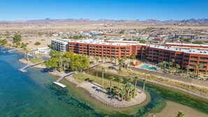 A hotel with multiple buildings, a swimming pool, and a dock extending into a clear blue lake.
