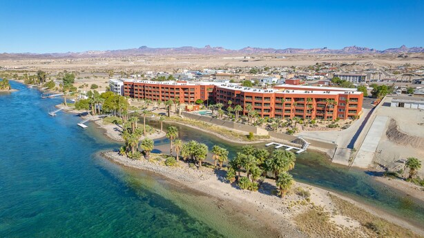 A hotel with a pool, palm trees, and a river.