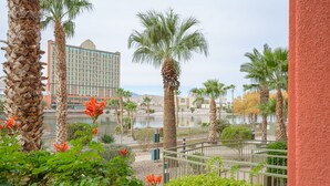 A hotel with a view of a body of water, palm trees, and a mountainous landscape in the background.